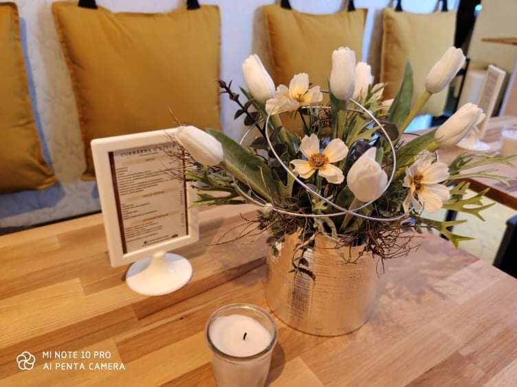 Útulný interiér cukrárny s květinami a svíčkou